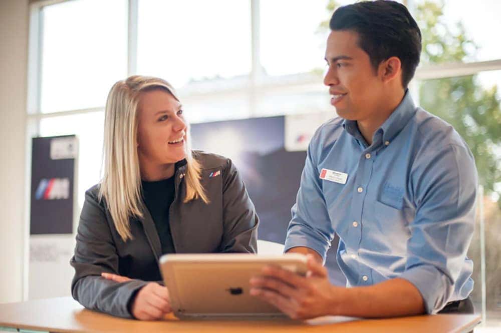 Smiling people are shown looking at a tablet.