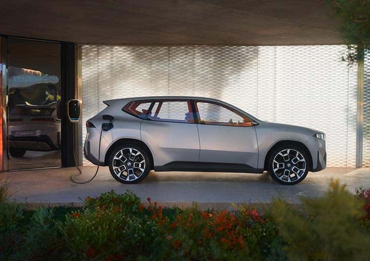 A silver BMW Vision Neue Klasse X is shown from the side charging.