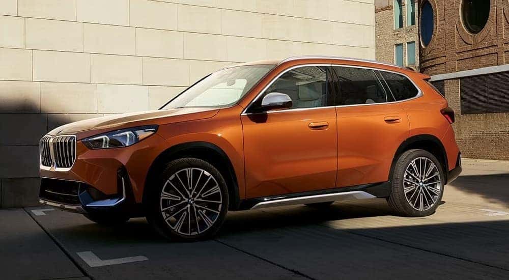 An orange 2024 BMW X1 parked in the city.