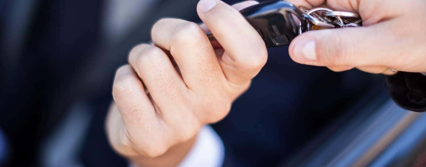 A salesman is handing a key to a customer that signed a BMW lease deal.