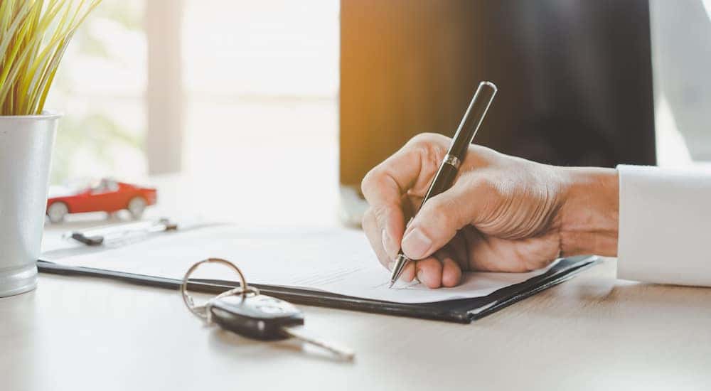 Close-up of a customer signing paperwork for a BMW lease deal.