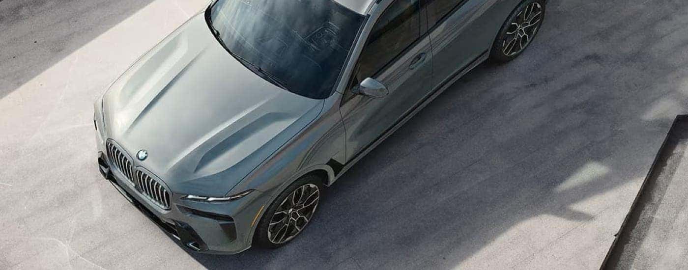 A grey 2024 BMW X7 is parked outside of a BMW dealer.