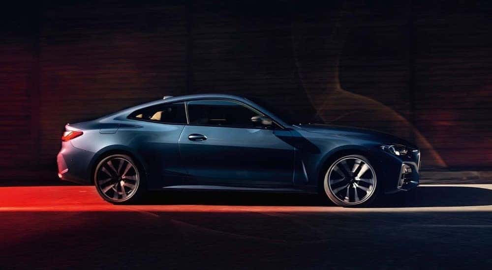 A blue 2024 BMW M440i is shown from the side driving to a BMW dealer in McKinney.