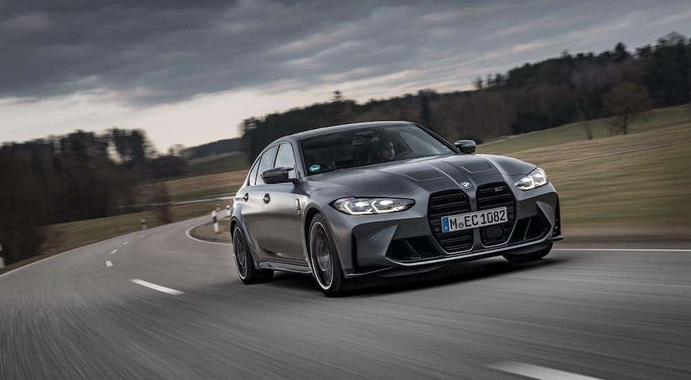 A grey 2024 BMW M3 is shown from the front at an angle.