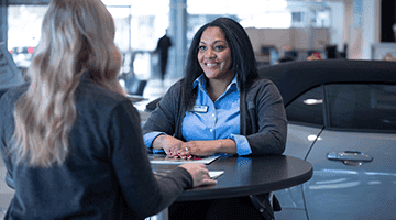 two women sitting across from each other at dealership