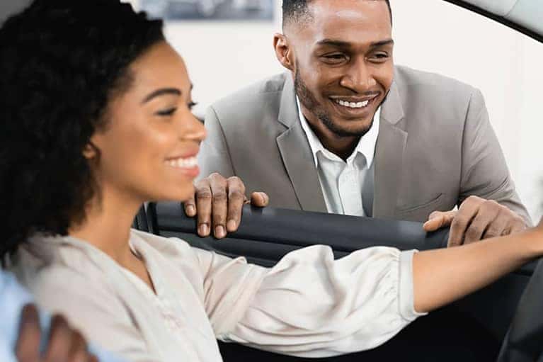 Happy customers review the interior dashboard and settings for their new car