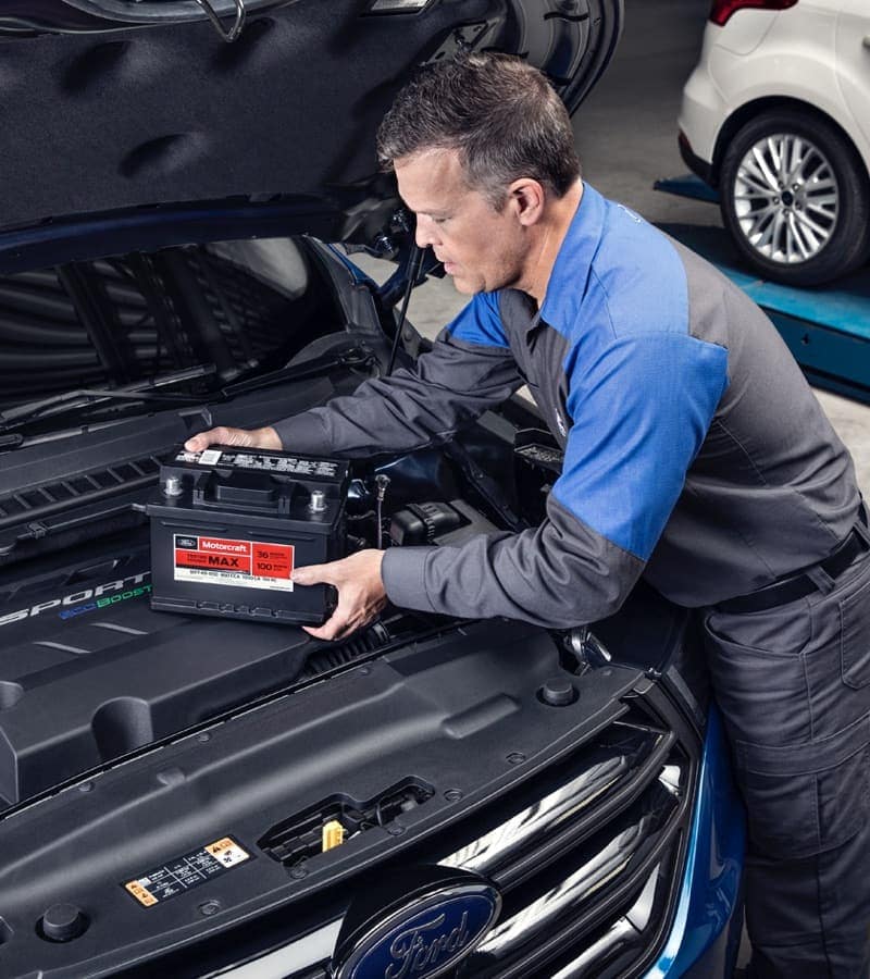 Mechanic working in engine bay of Ford vehicle