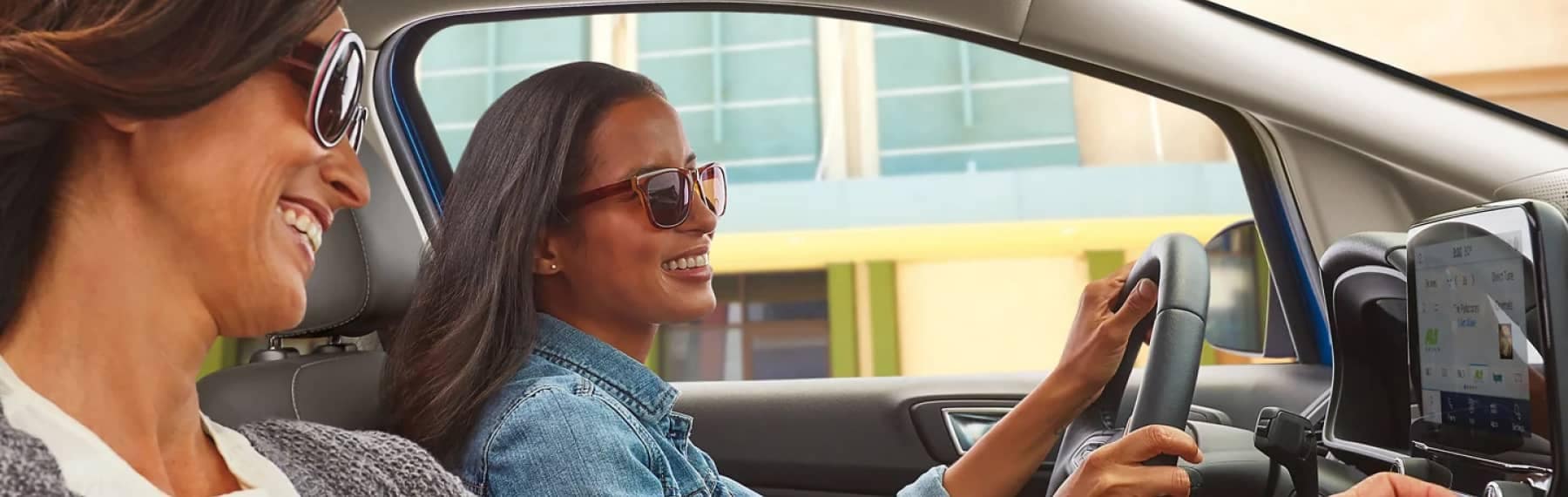 Girl wearing sunglasses Driving and Smiling with older woman in Passenger