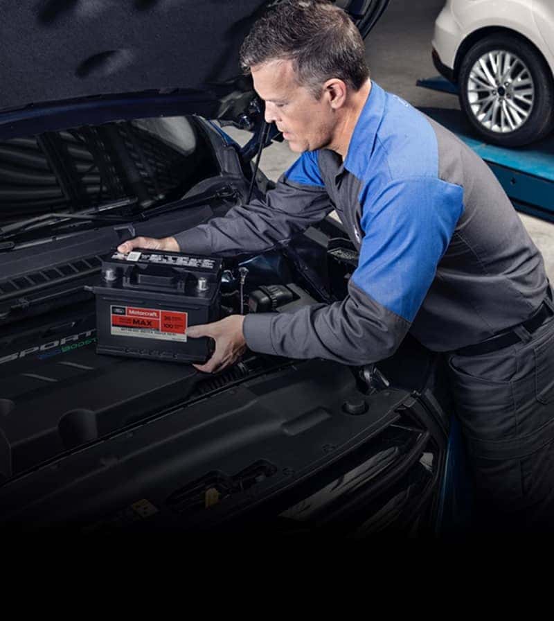 Mechanic working in engine bay of Ford vehicle