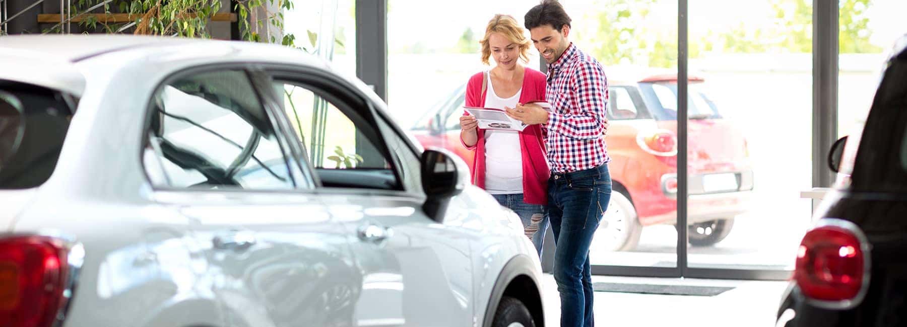 a young couple reading over paperwork in a car dealership