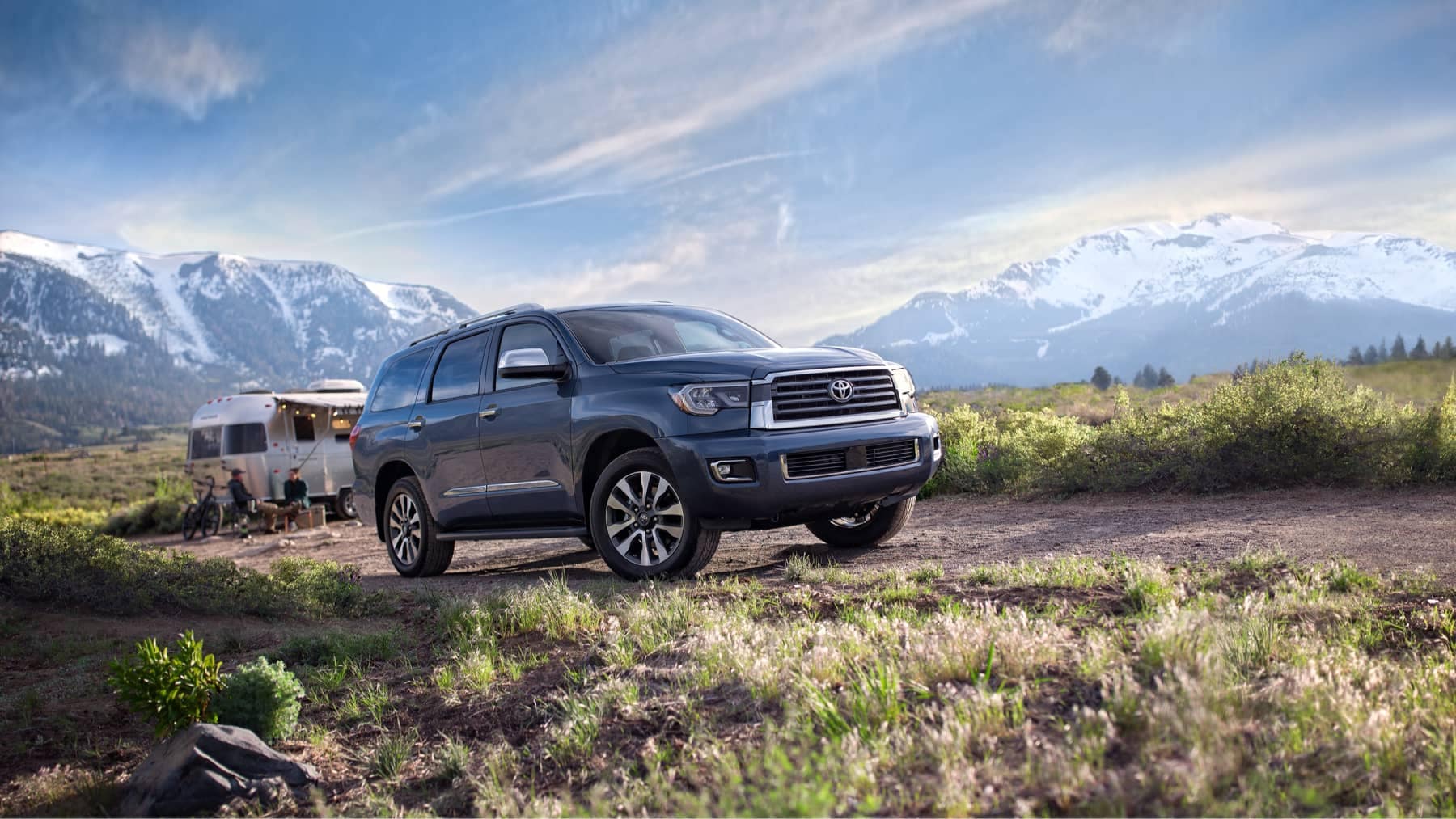 2021 Toyota Sequoia parked by a camper in the mountains