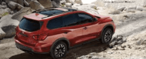 Red Nissan SUV against a rocky road backdrop.