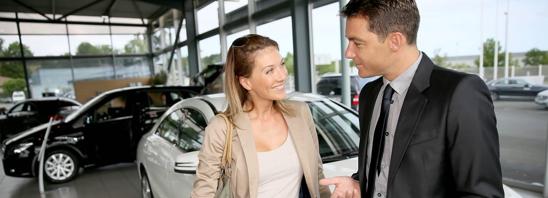 Car salesman discussing a car purchase with a female customer inside the showroom