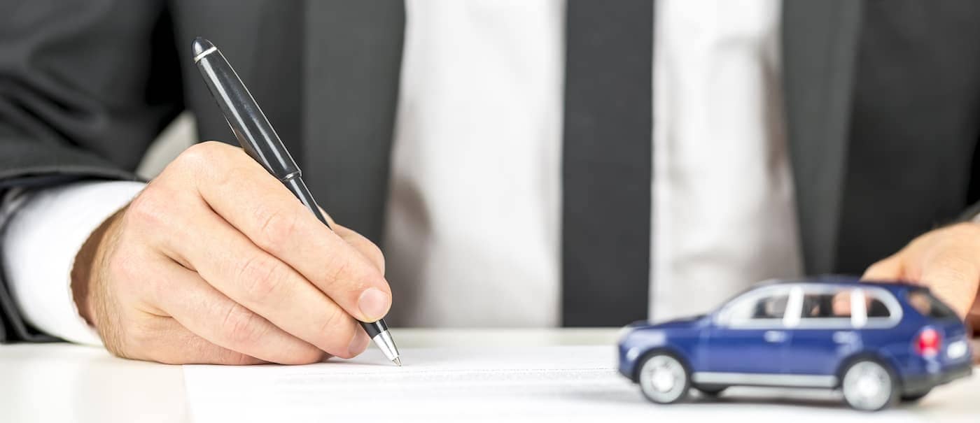 Closeup of man signing a contract of car sale.