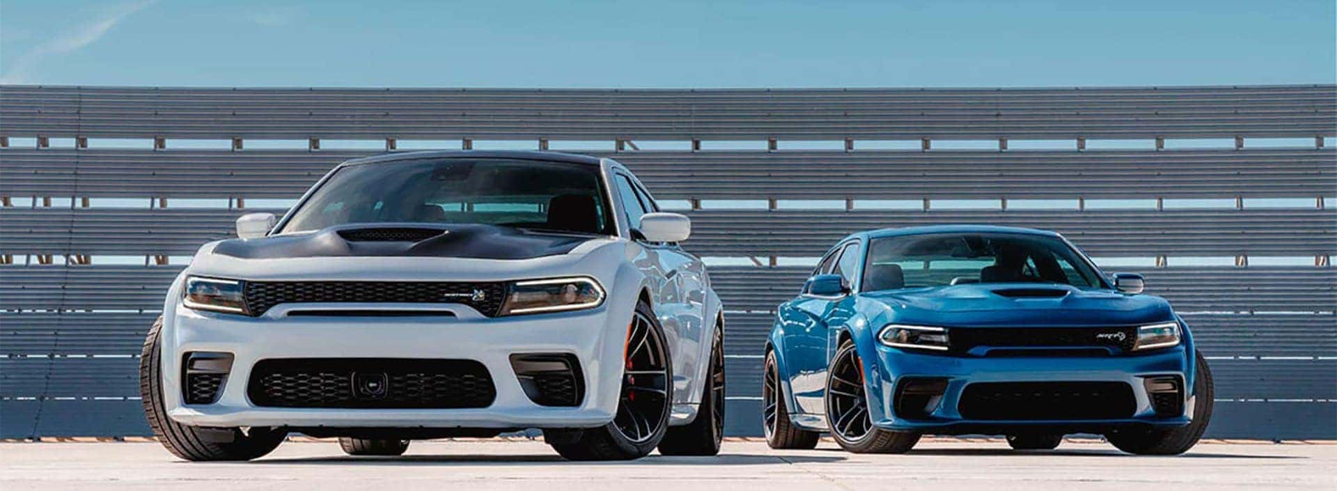 A white sedan and a blue sedan parked next to each other