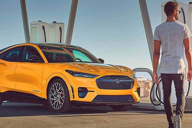 Man walking towards a yellow 2023 Mustang Mach-E