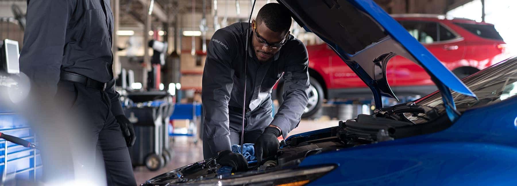Certified technician examines under car hood