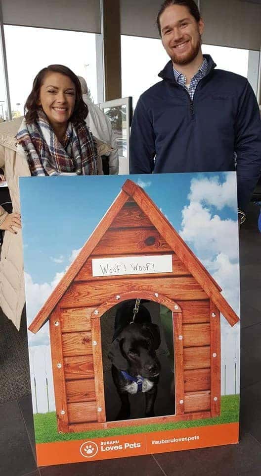 Man and woman taking a picture with a dog they just adopted