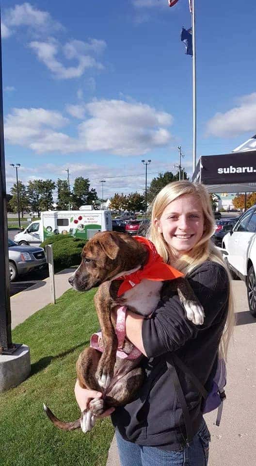 Woman holding adopted dog in her arms outside of the dealership