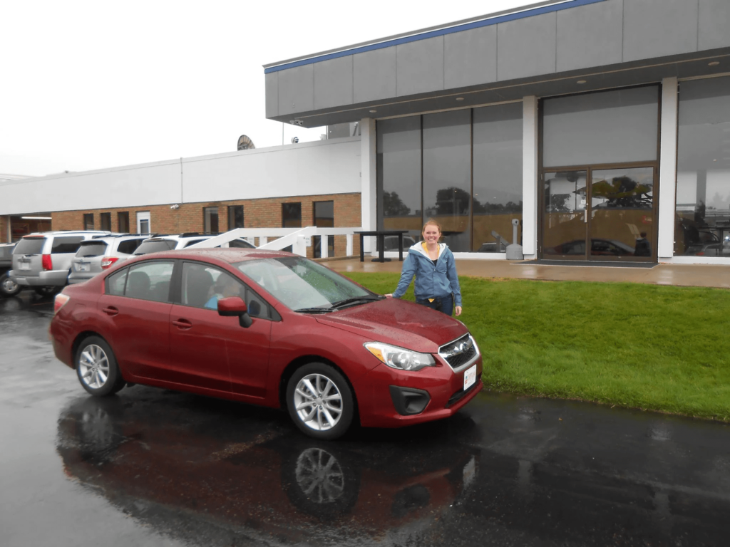 happy customer in front of the new subaru