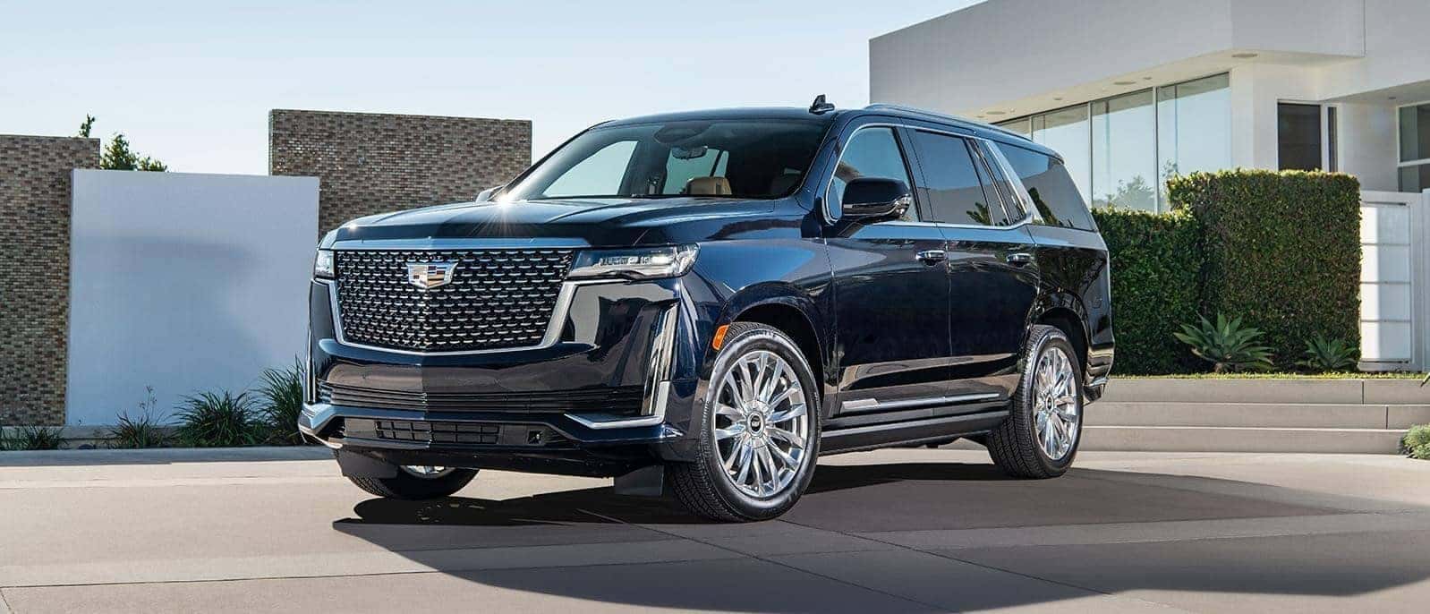 Black Cadillac SUV parked at an angle in front of a house