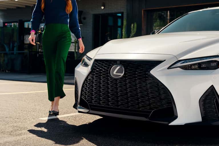 2024 Lexus IS front of vehicle with woman in green pants walking by