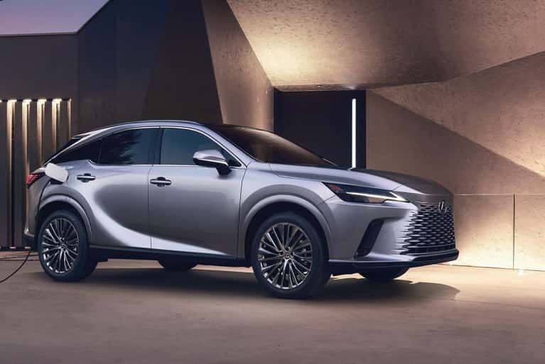 2024 Lexus RX parked by a modern house and plugged into electric charger