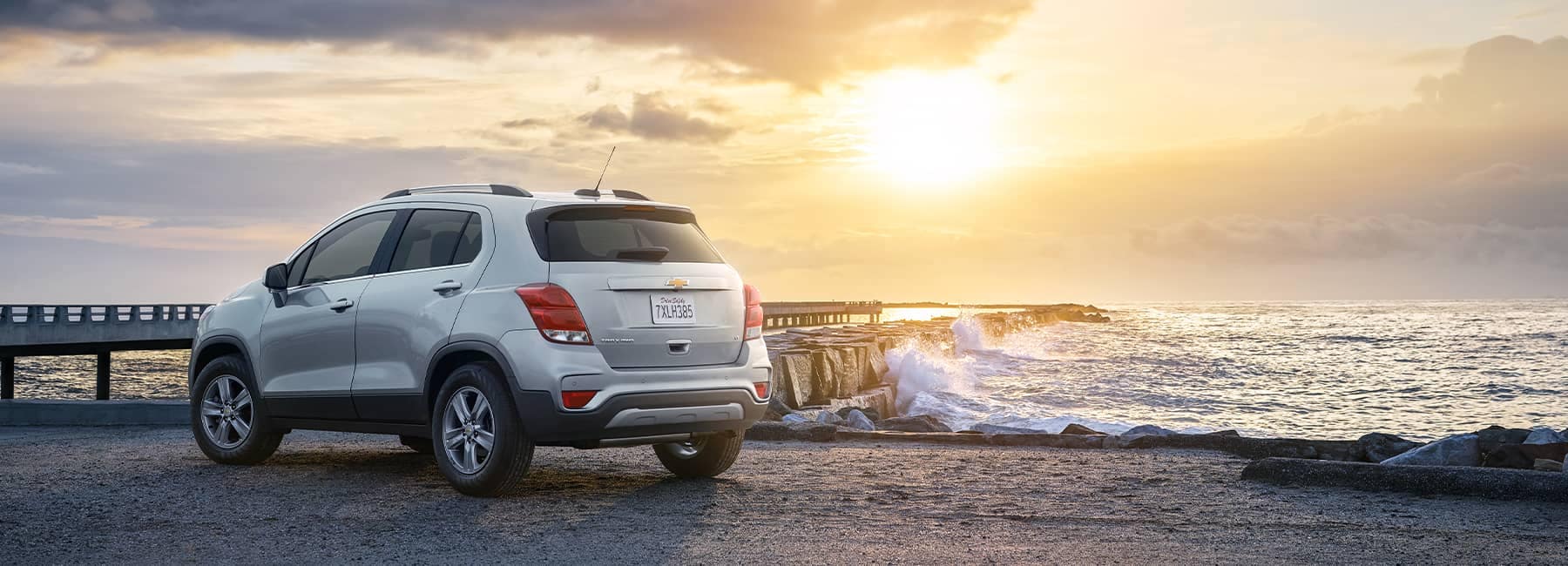 Rear view of a white 2021 Chevrolet Trax parked in front of an ocean pier