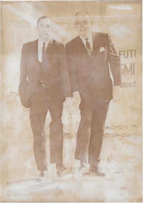 Bill-and-steve-smith-in-suits-with-foot-on-shovel