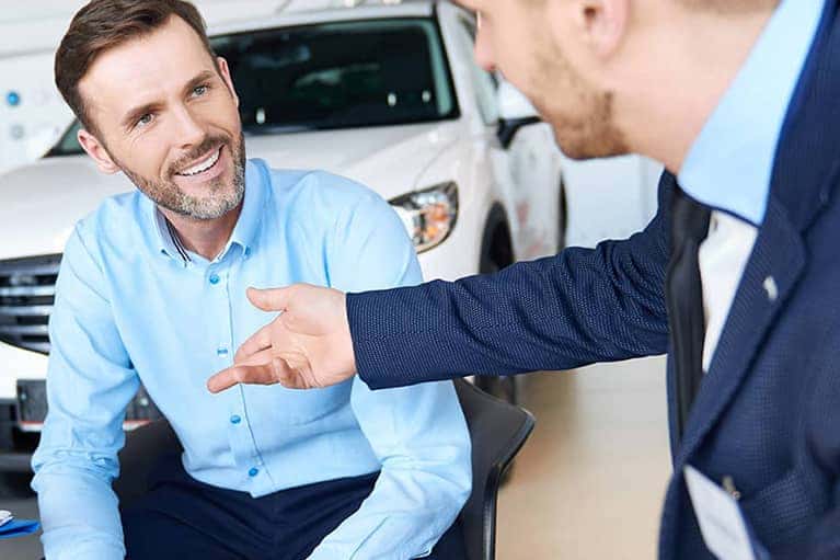 smiling man meets finance officer car showroom