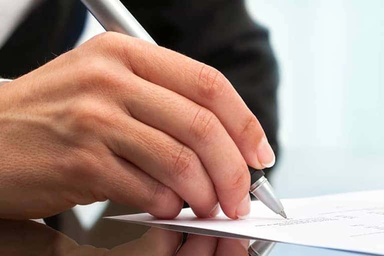man signs papers in well lit room