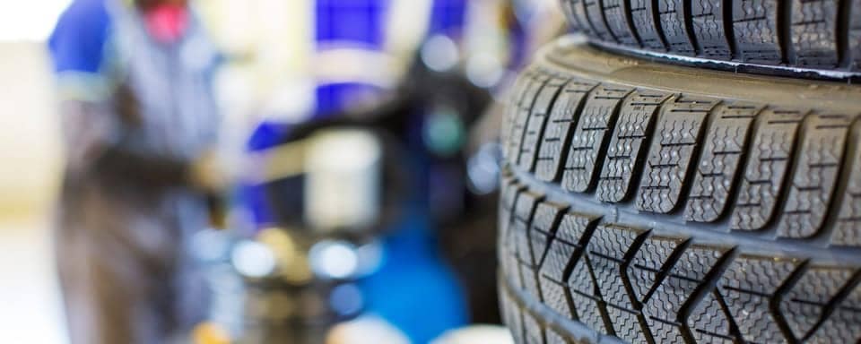 Tires stacked on each other with a blurred background of a service shop