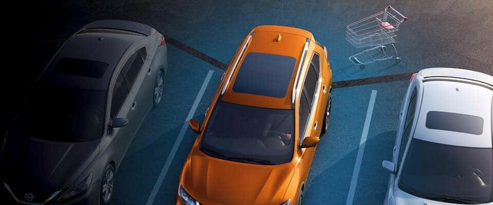 Nissan Rogue Tech Feature And orange Nissan Rogue using a tech feature to sense a shopping cart behind it