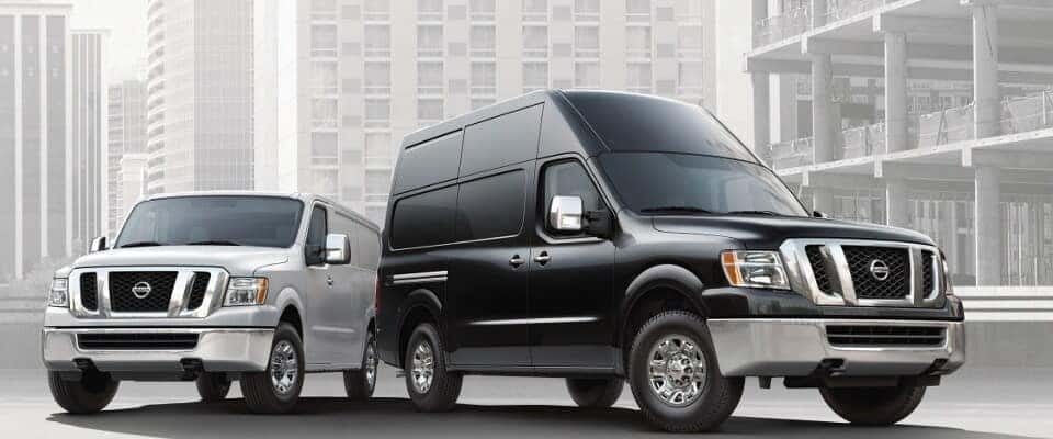 A grey and black Nissan NV Cargo and Passenger Van parked next to each other