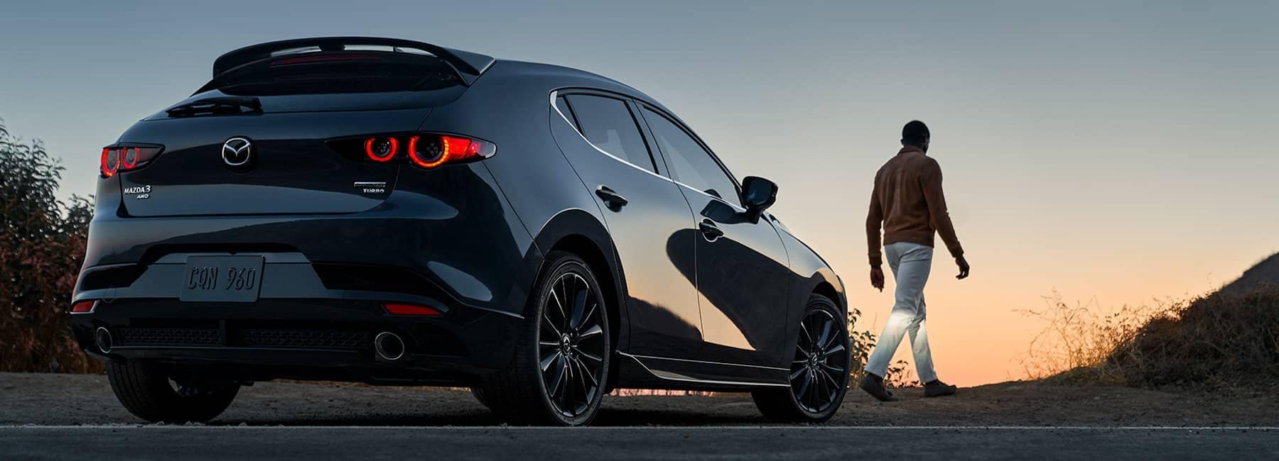 2022 Mazda 3 Hatchback-rear-3qview-parked-man-walking-sunset-black