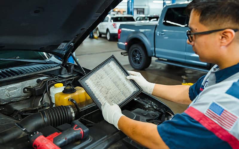 Service Tech is changing air filter on a Ford vehicle.