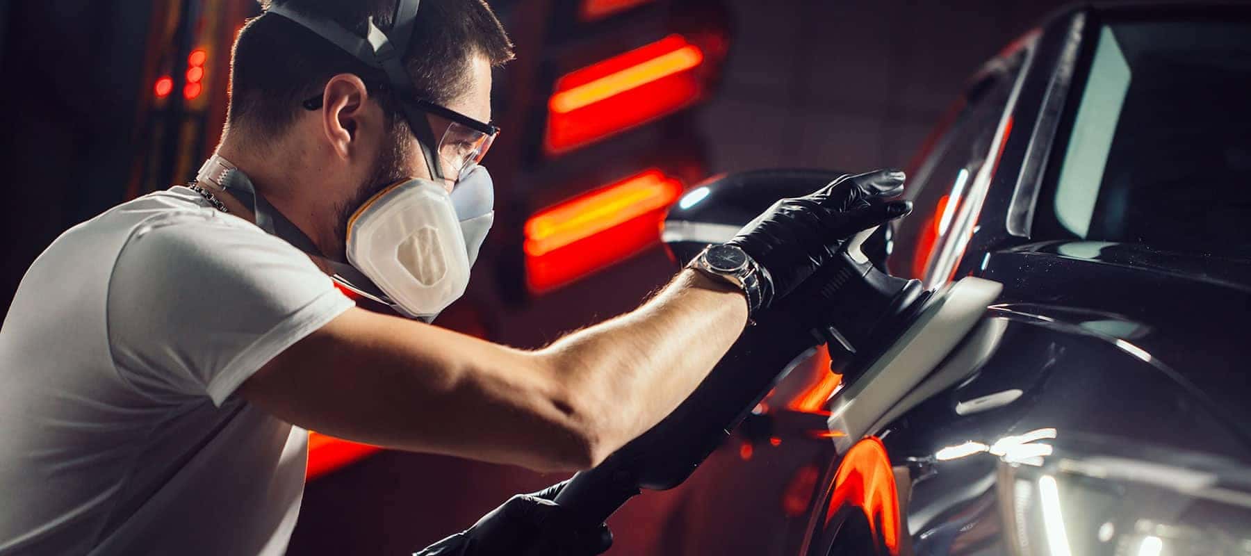 Man buffing a car with a respirator on