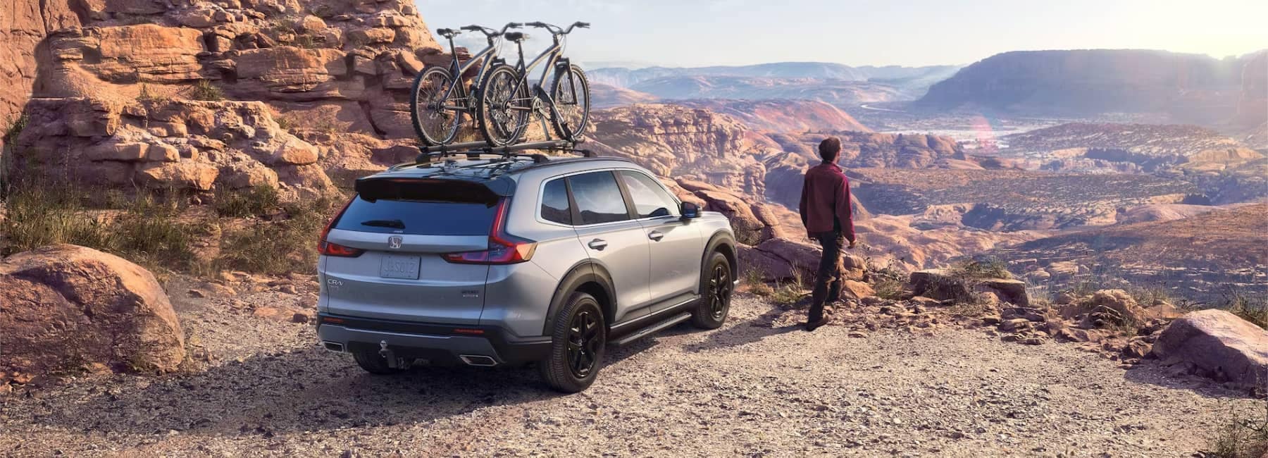 Grey Honda CR-V in the desert with two mountain bikes on the roof rack