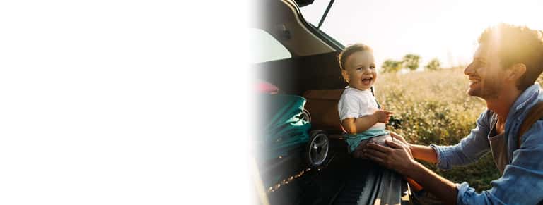 Father and son by vehicle's open trunk