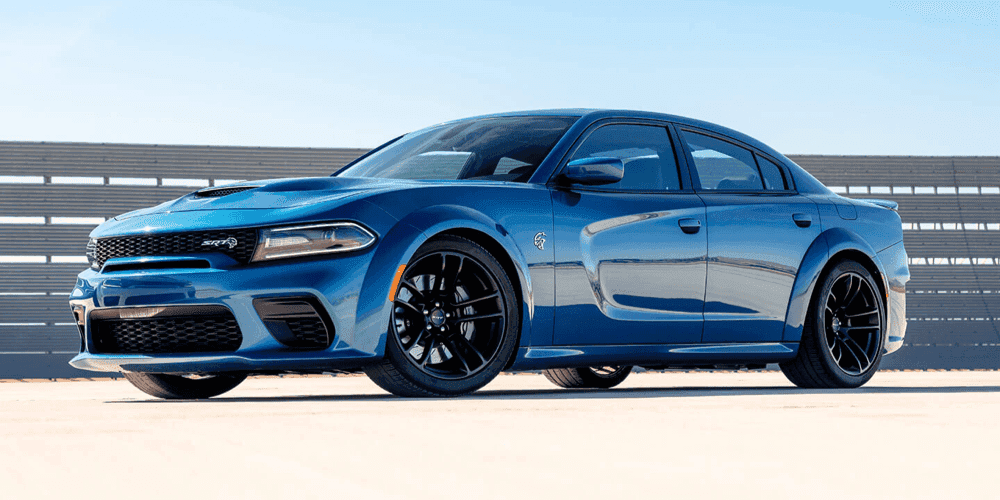 blue Charger parked in front of fence