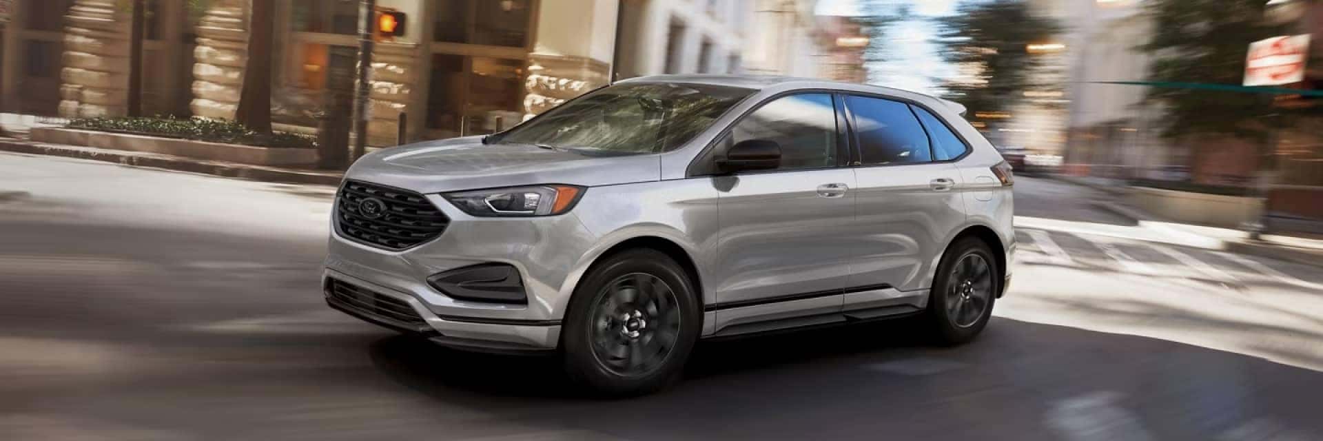 2024 Silver Ford Edge driving down a road