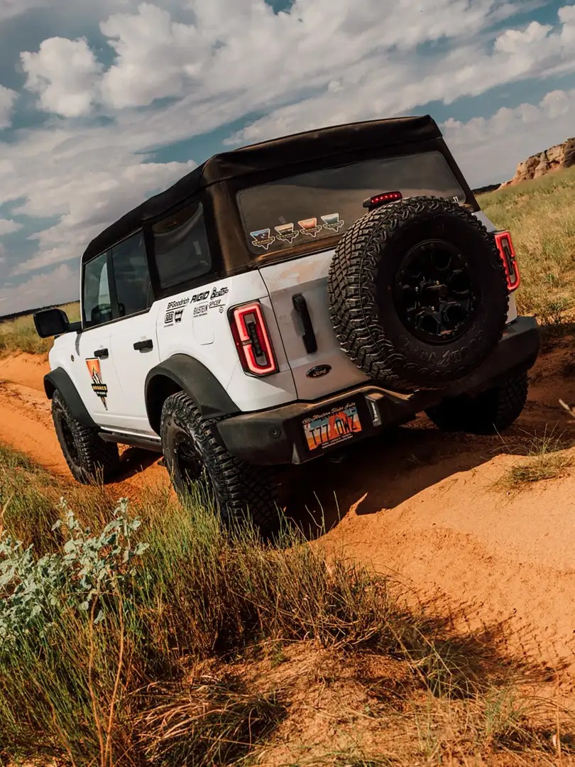2026 Ford Bronco Rear View Wide Rock driving down a sandy desert road