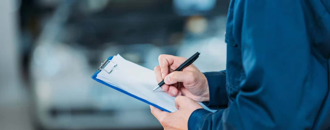 Service-technician-writing-on-a-clipboard-of-paperwork