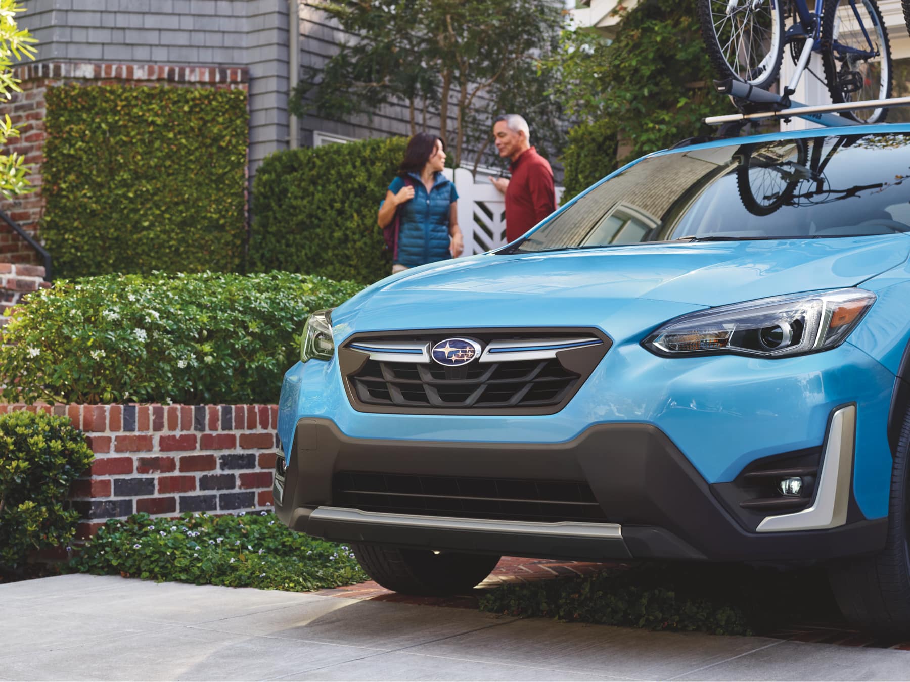 2022 Subaru Crosstrek Hybrid with bicycles mounted on top and parked in front of brick house
