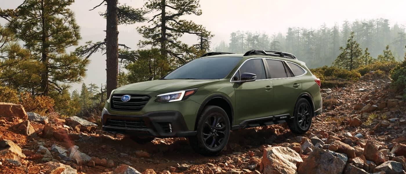 Green Subaru Outback on a rocky forest path