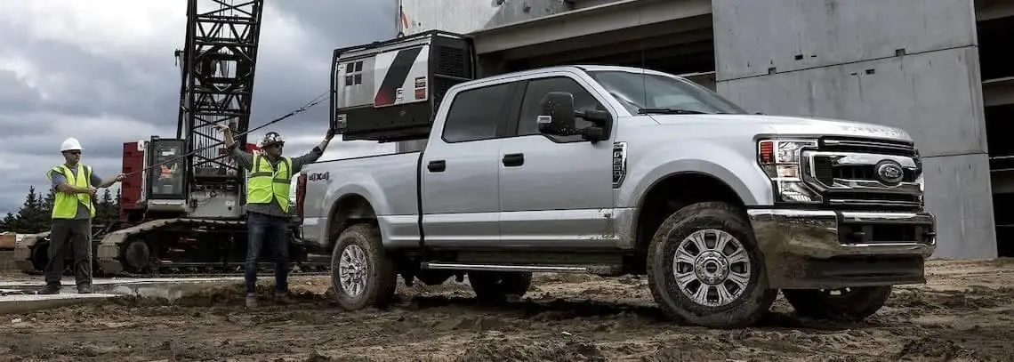 Ford F-250 4x4 being loaded with a generator at construction site