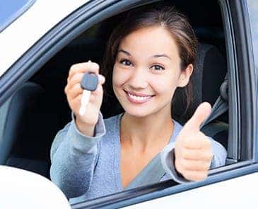 Woman in car holding keys giving a thumbs up