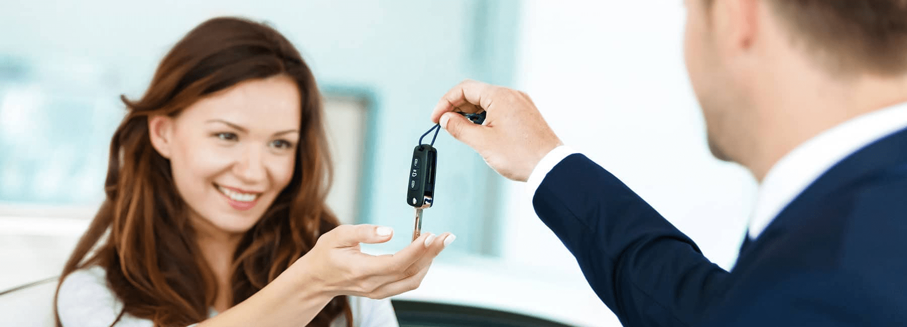 happy woman receives car keys from car dealer