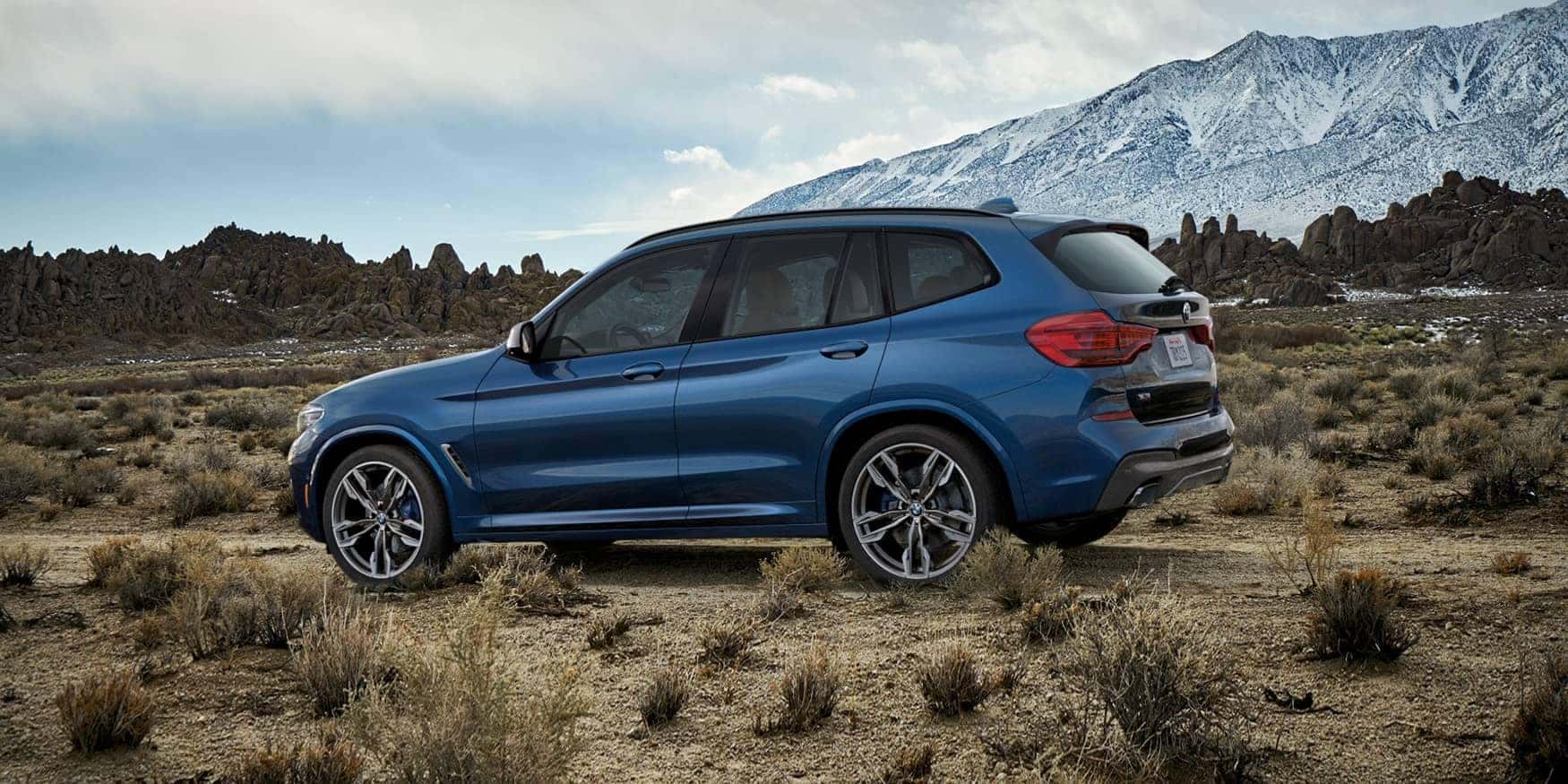 Blue 2020 BMW x3 driving on dirt road