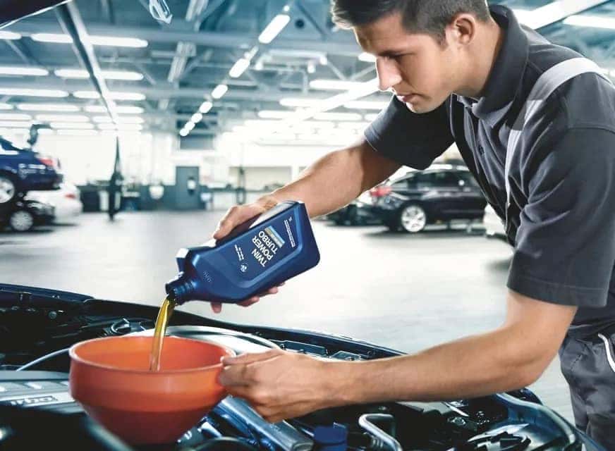 BMW mechanic pouring oil into engine